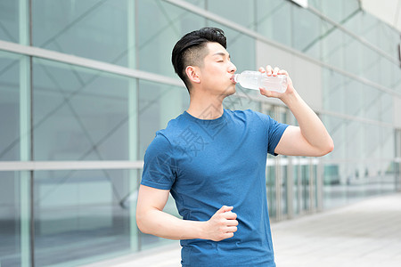 运动健身后站着喝水的年轻男性图片