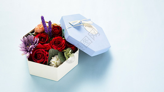 蓝色背景上装满鲜花的礼物盒图片