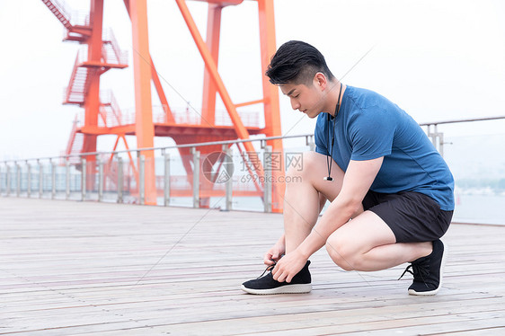 蹲着系鞋带的运动男性图片