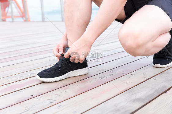蹲着系鞋带的运动男性图片