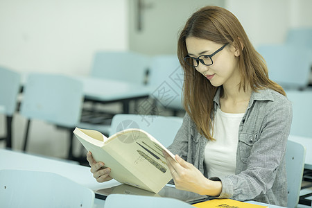 戴眼镜模特女学生在大学教室里学习背景