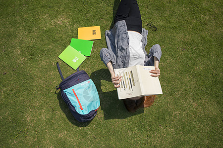 女学生躺在大学草坪上看书高清图片