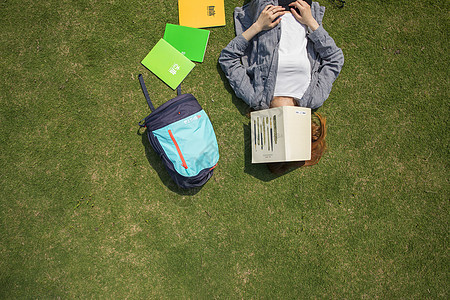 女学生躺在大学草坪上看书图片