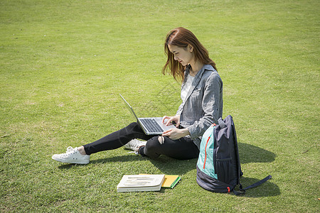 女学生在大学草坪上看电脑图片