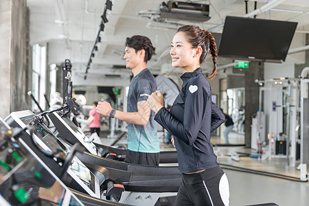 年轻女性健身房使用跑步机跑步高清图片