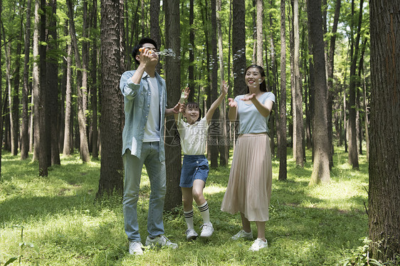 父母与孩子在树林中吹泡泡图片