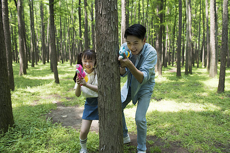 爸爸与孩子在树林中玩水枪图片