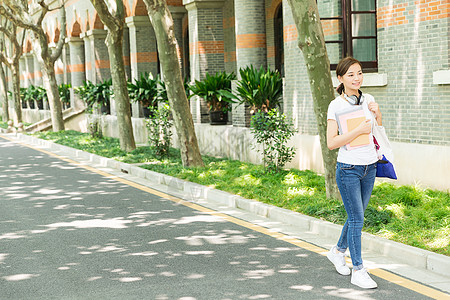 青春大学生抱着书本走路高清图片