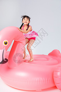 在火烈鸟上玩耍的泳装小女孩图片