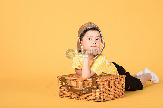 趴在行李箱上戴着飞行帽的小朋友图片