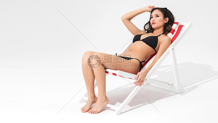 黑色比基尼泳装美女坐在沙滩躺椅上图片