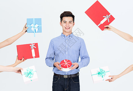年轻男性抱着一推礼物盒高清图片
