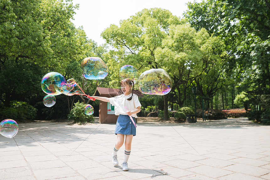 公园里可爱女孩玩吹泡泡图片