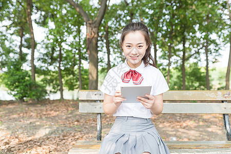 学院风女生林荫道拿平板电脑图片