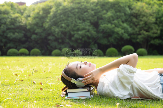 青春学生躺草地上听音乐图片