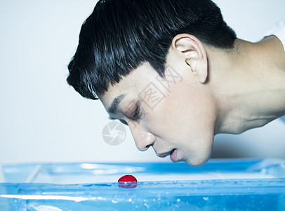拿着樱桃在水面放空的青年男性图片