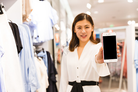 手机支付青年女性女装店手持手机背景