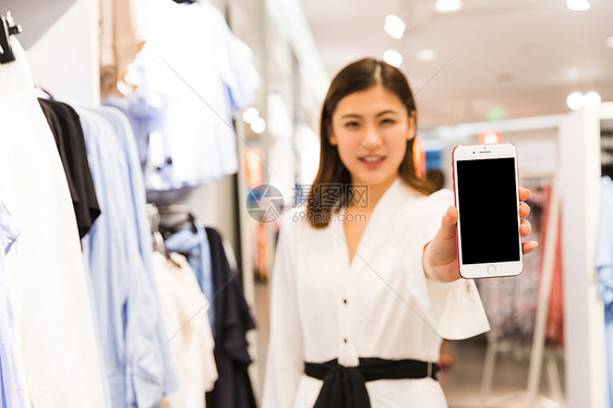 青年女性女装店手持手机图片