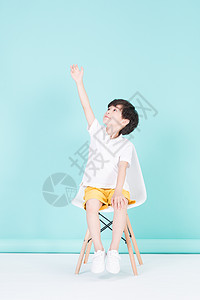 坐在凳子上举手的小男孩教育图片