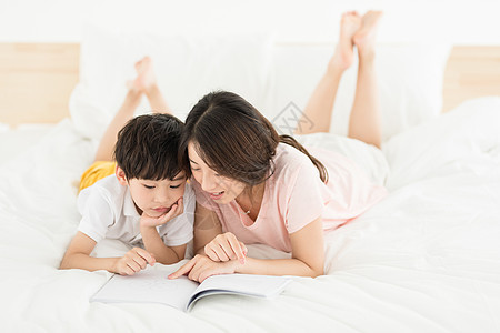 妈妈陪伴儿子在床上看书图片