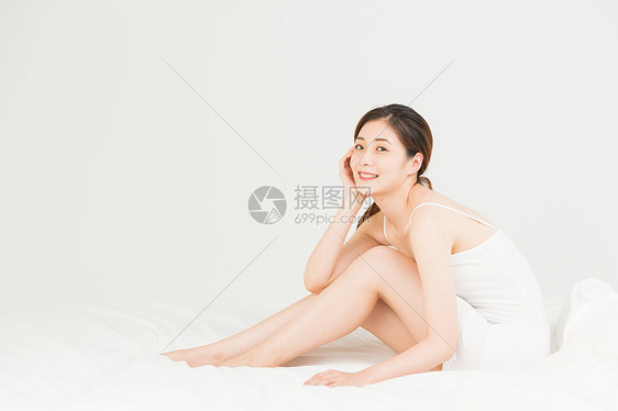 年轻女性坐床上休息图片