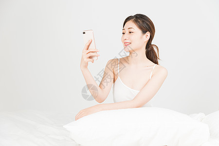 年轻女性床上手机自拍图片