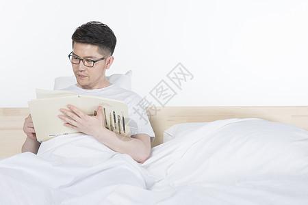 男性在床上阅读图片