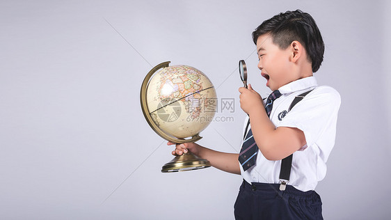 男孩用放大镜探索地球仪图片