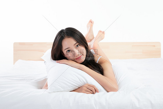 年轻女性趴在床上玩图片
