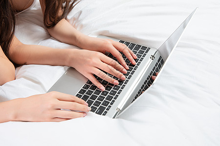 年轻女人闺蜜床上一起玩电脑背景