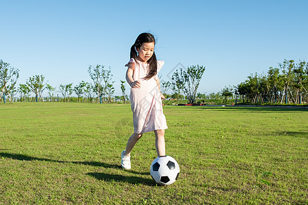 小孩子草地上踢足球背景图片