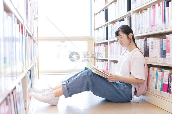 背靠书架看书的女生图片