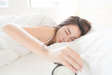 年轻女性起床困难按闹钟高清图片