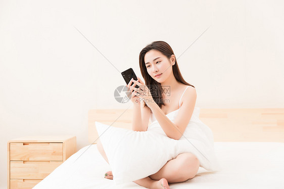 年轻女性床上休息看手机图片