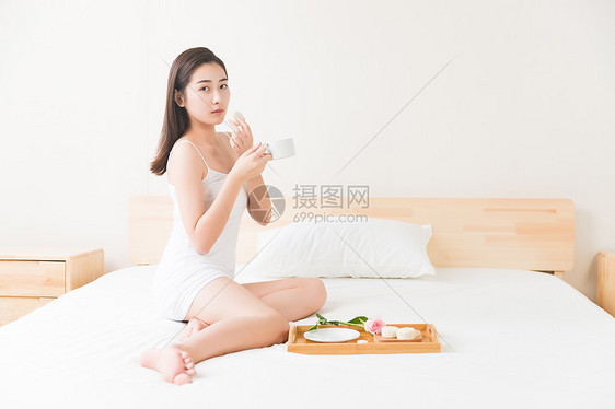 年轻美女在床上吃早餐图片