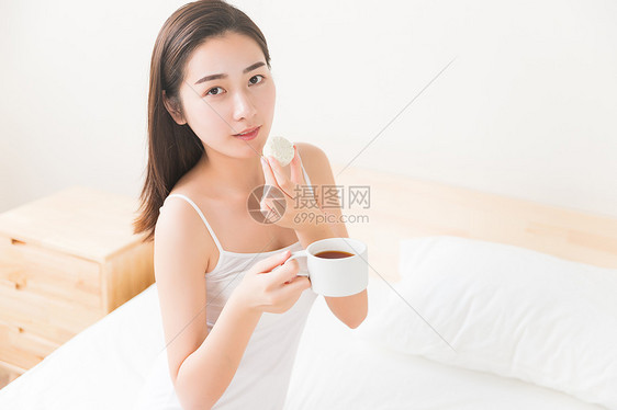 年轻美女在床上吃早餐图片