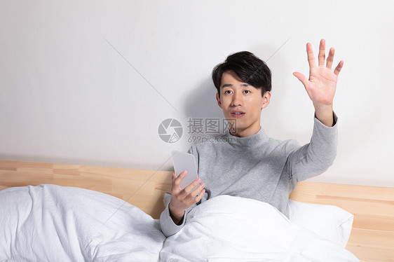 躺在床上玩手机的男性图片