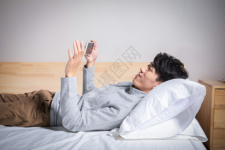 虚拟交互躺在枕头上玩手机的男人背景