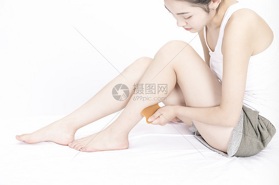 女性用刮痧板按摩腿部图片