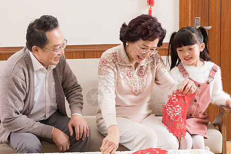 春节爷爷奶奶教孩子剪窗花图片