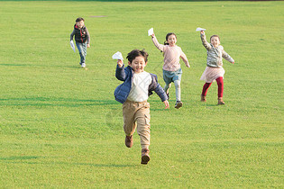 草地上玩纸飞机的孩子们图片