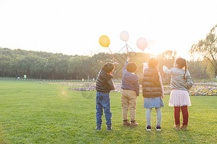夕阳下拿着气球的儿童们图片