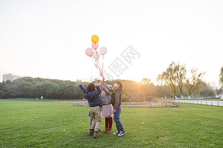 夕阳下儿童们共同放气球背景