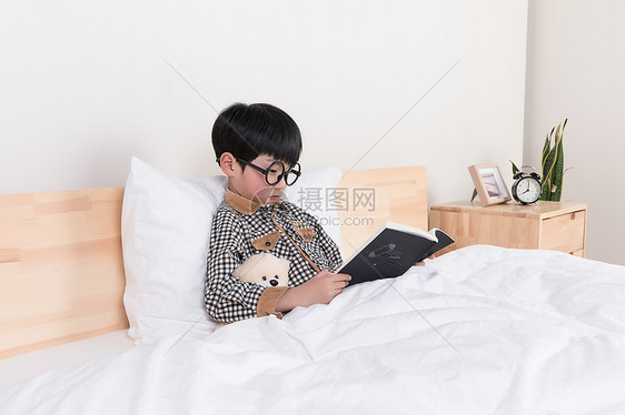 在床上看书的小男孩图片