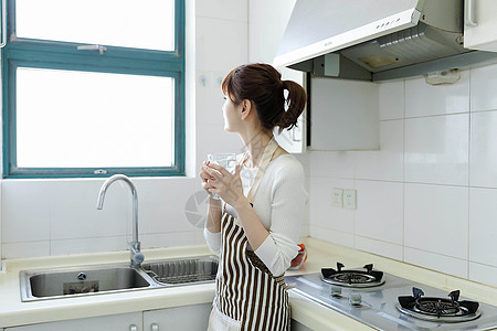 厨房里喝水的家庭主妇图片