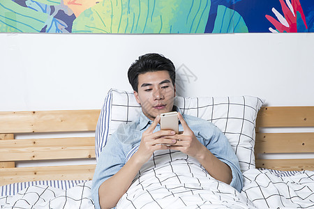青年男性起床床上玩手机图片