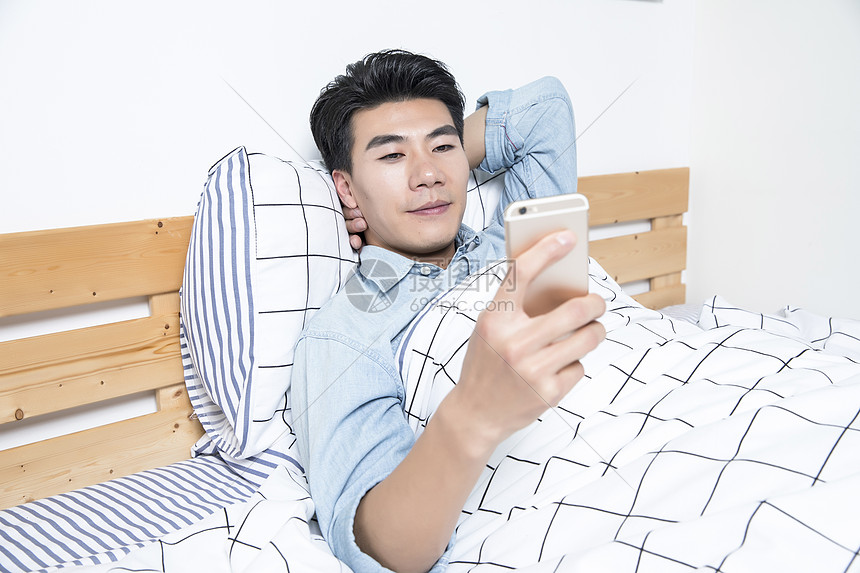 青年男性起床床上玩手机图片
