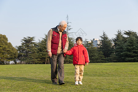 蓝天草地公园祖孙情爷爷牵孙子散步背景