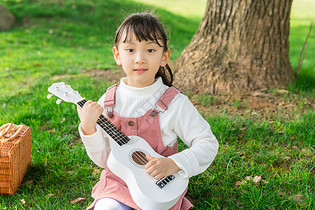 女孩在草坪上弹吉他图片