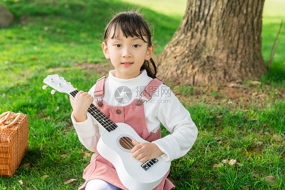 女孩在草坪上弹吉他图片